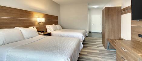 A hotel room with two beds, a wooden headboard, a TV, and a wardrobe.