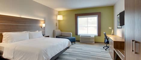 Een hotelkamer met een groot bed, een bureau, een stoel, een televisie en een raam.