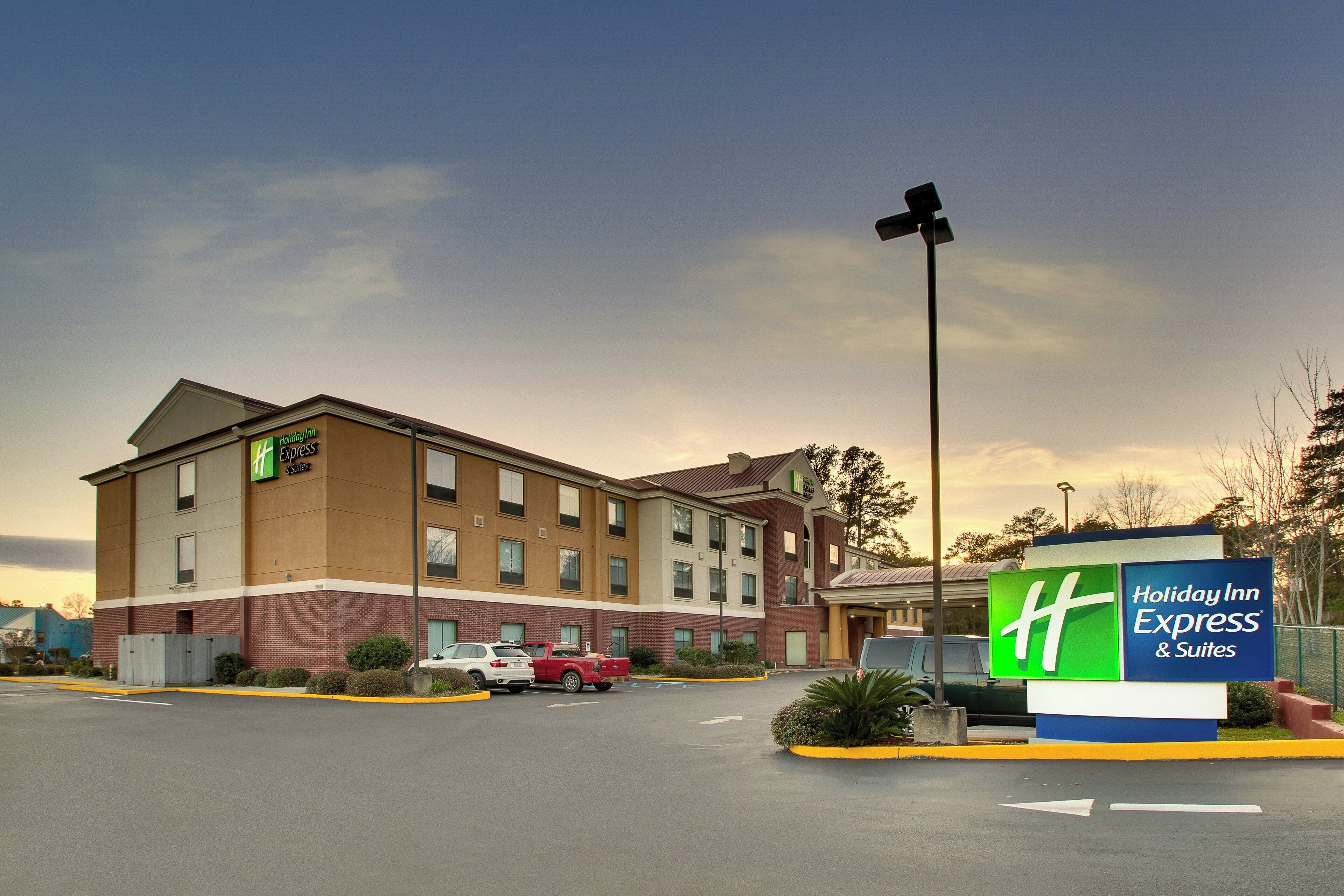 A Holiday Inn Express building with a brick facade, multiple windows, and a parking lot with several cars.