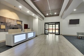 A reception area with a modern design, featuring a reception desk, a wall-mounted information board, and a seating area with a chair. - Holiday Inn Express & Suites Laurel by IHG (Laurel)
