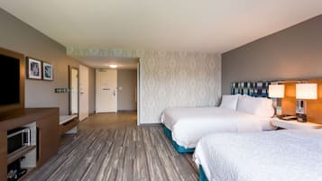 A hotel room with two beds, a TV, a desk, and a lamp.