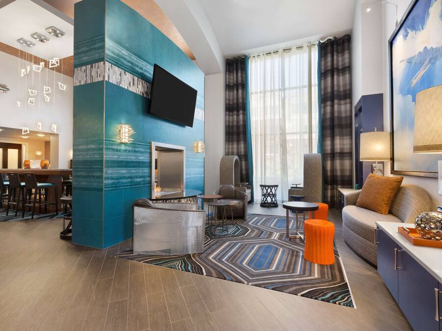 Un moderno vestíbulo de hotel con bar, zona de estar y una gran pantalla de televisión.