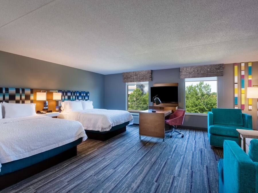 Een hotelkamer met twee bedden, een bureau, een stoel en een televisie.