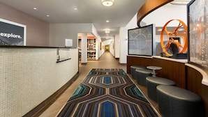 A hotel lobby with a patterned carpet, seating area, and a reception desk.