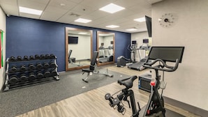 A gym with exercise equipment, a mirror, and a clock on the wall. - Hampton Inn Jasper (Jasper)