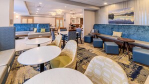 A modern hotel lobby with seating areas, tables, and a large landscape painting on the wall. - Hampton Inn Jasper (Jasper)