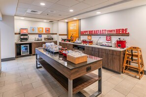 A modern breakfast area with a counter, coffee machine, and various food items.