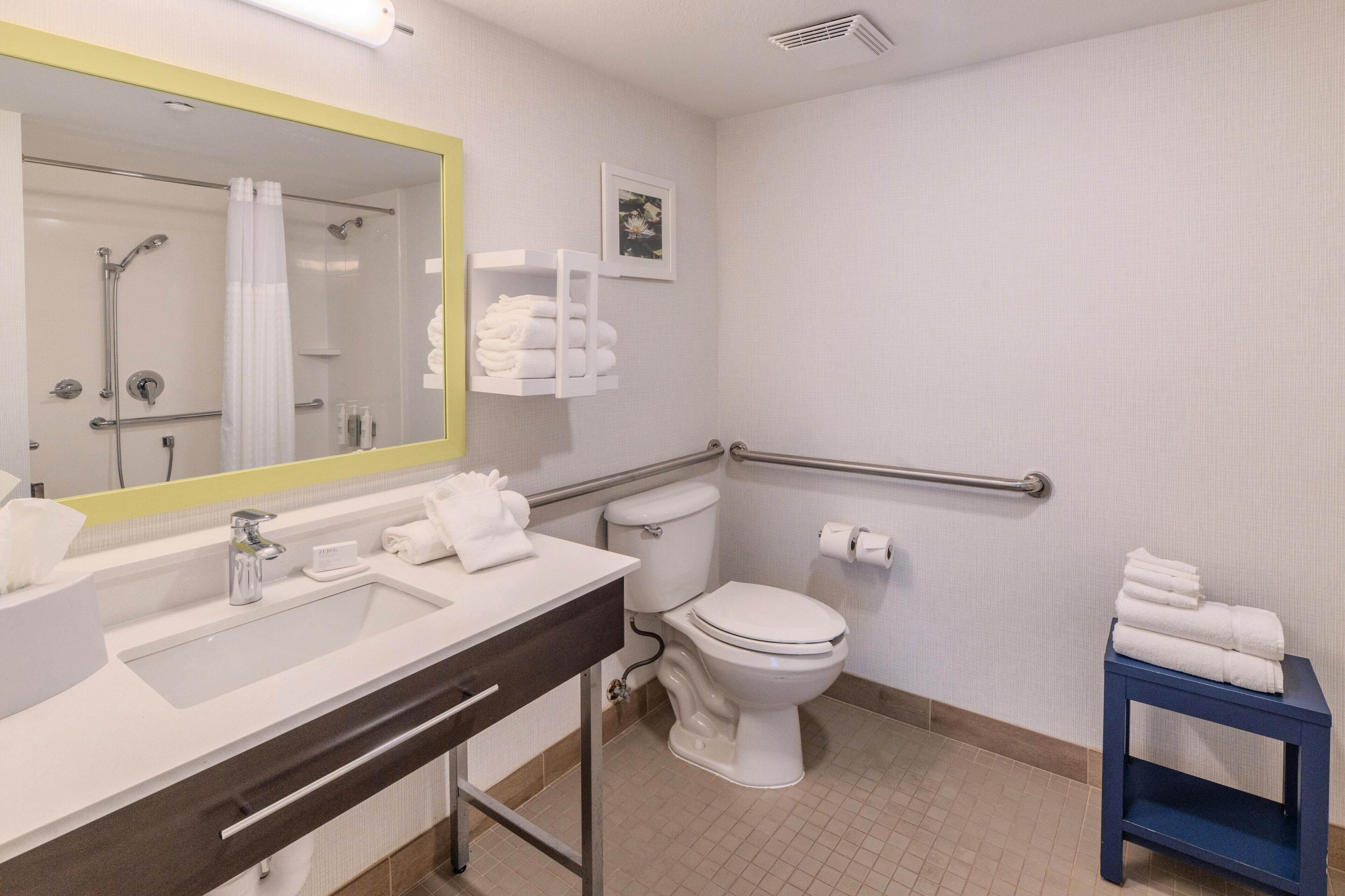 A modern bathroom with a large mirror, a sink, a toilet, and a shower.