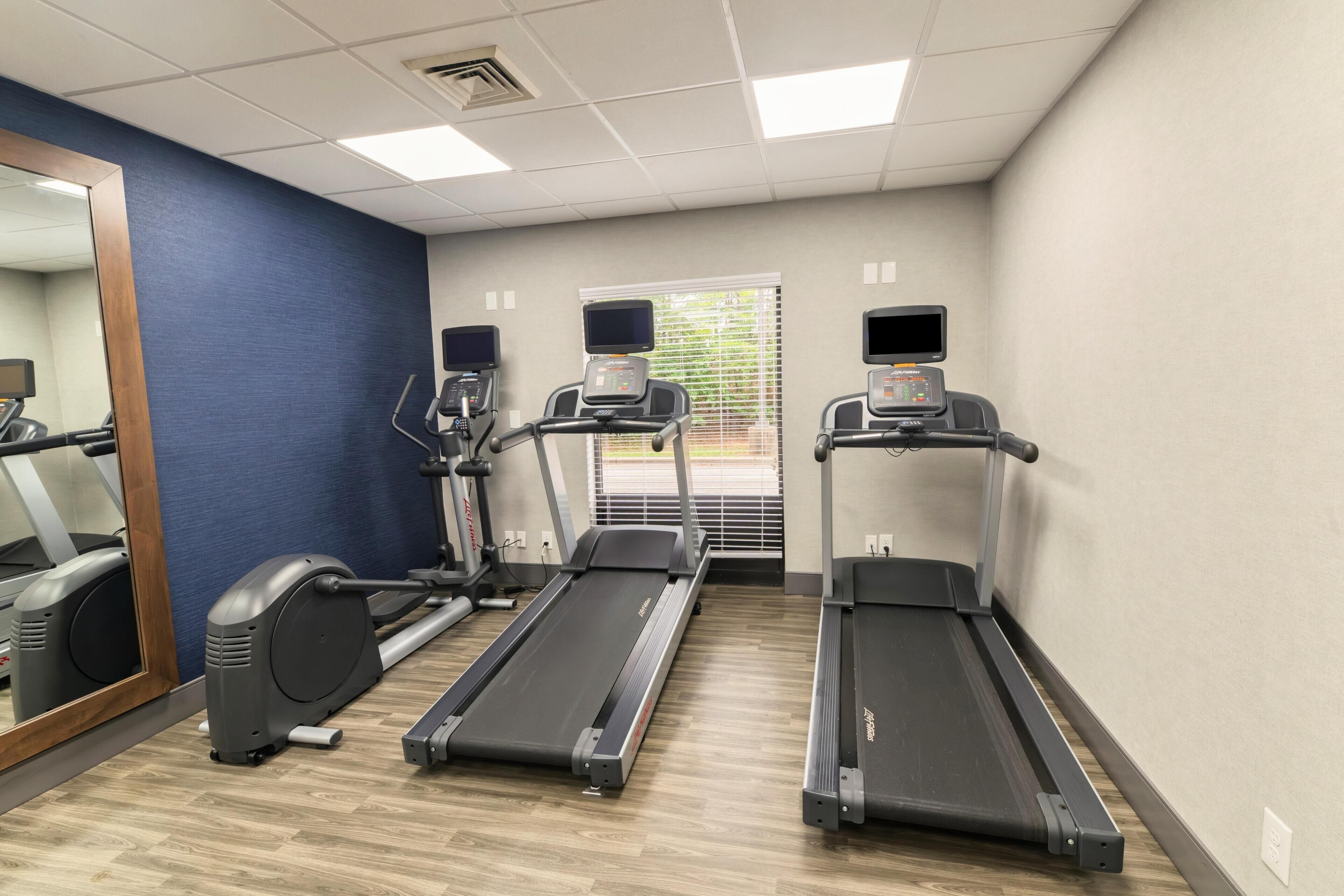 Une salle de remise en forme équipée de tapis de course, d’un appareil elliptique et d’un miroir.