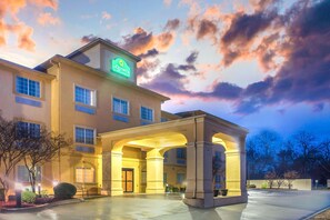 A hotel with a large entrance, a sign reading "La Quinta", and a clear sky with clouds.