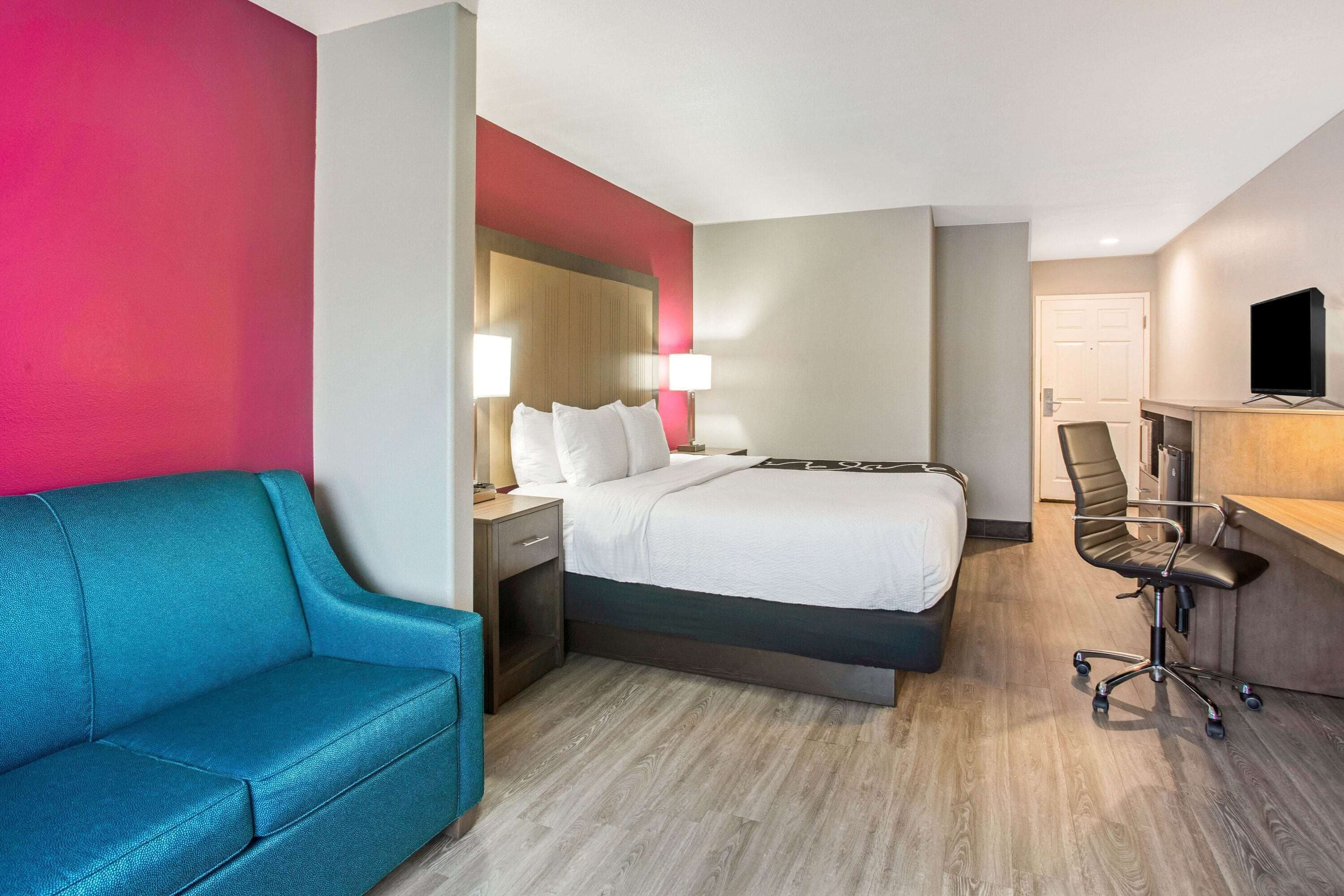 A hotel room with a bed, a desk, a chair, and a sofa.