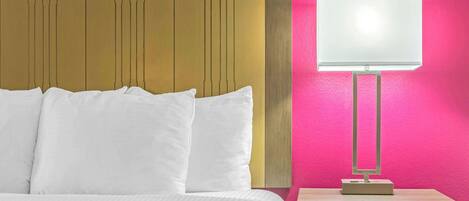 Una habitación de hotel con una cama, una mesita de noche con lámpara y un cabecero de madera.