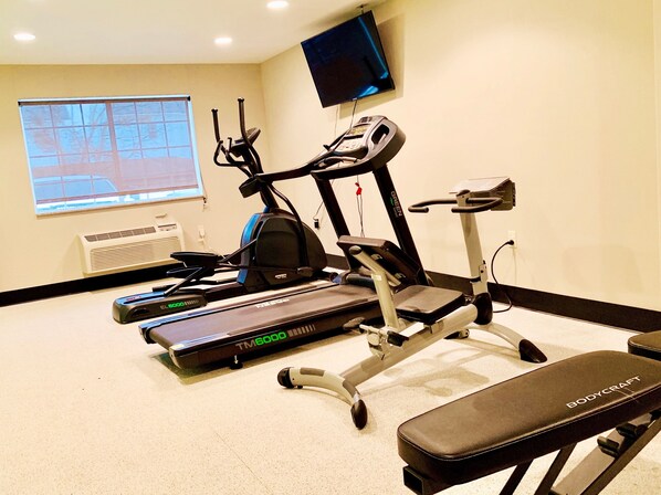 A gym with treadmills, an elliptical, and a bench.