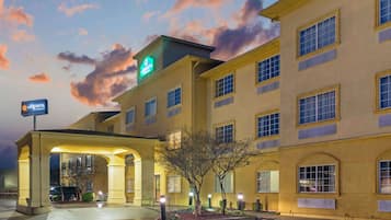 A hotel with a large sign for La Quinta, featuring a covered entrance and a well-lit facade.