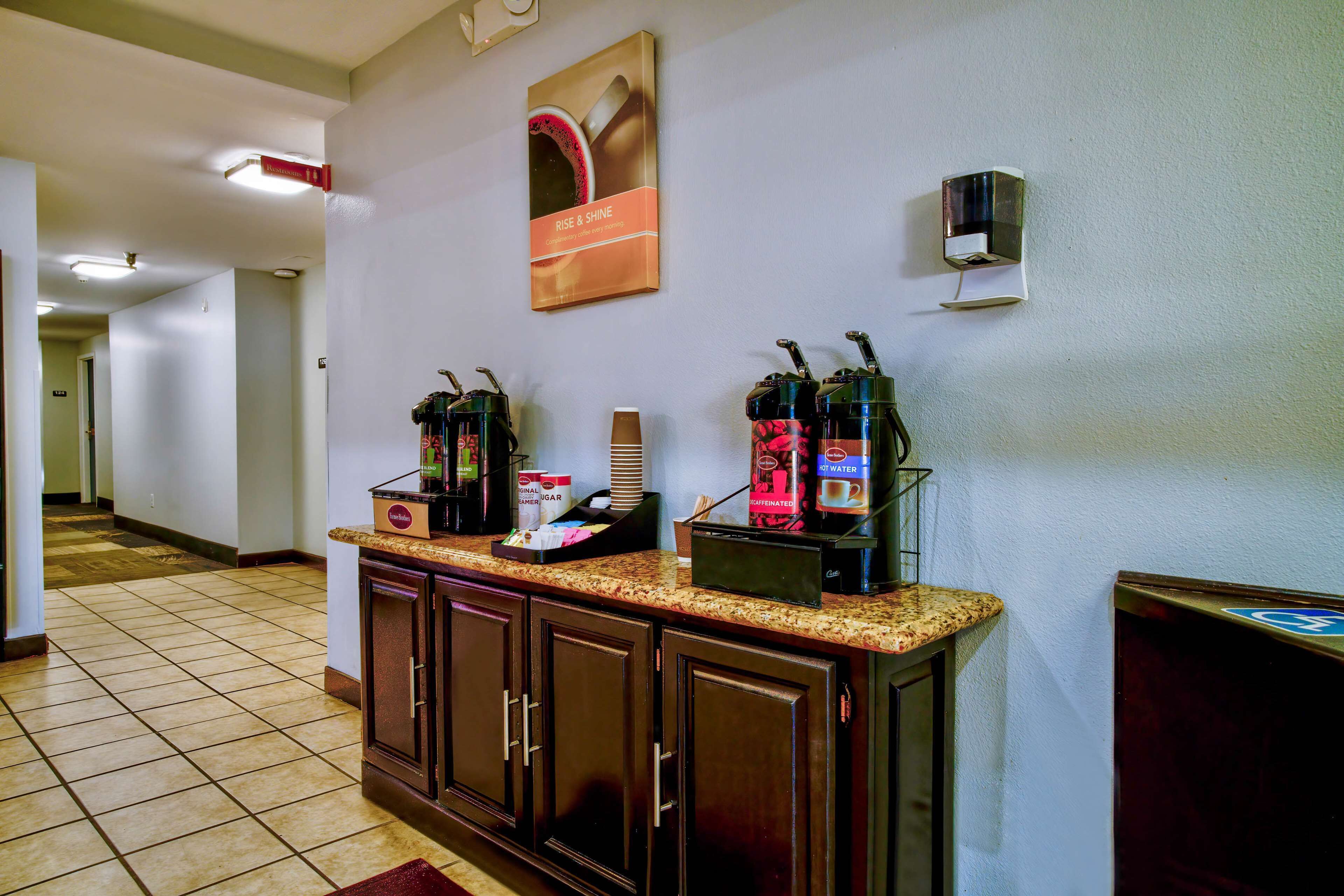 A hotel reception area with a coffee station, a bulletin board, and a waste bin.