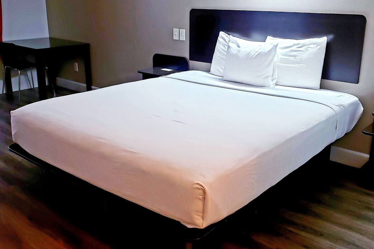 A hotel room with a large bed, a desk, and a chair.