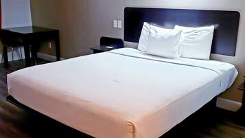 Una habitación de hotel con una cama grande, un escritorio y una silla.