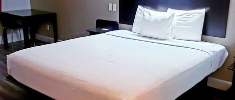 Quarto de hotel com uma cama grande, uma mesa e uma cadeira.