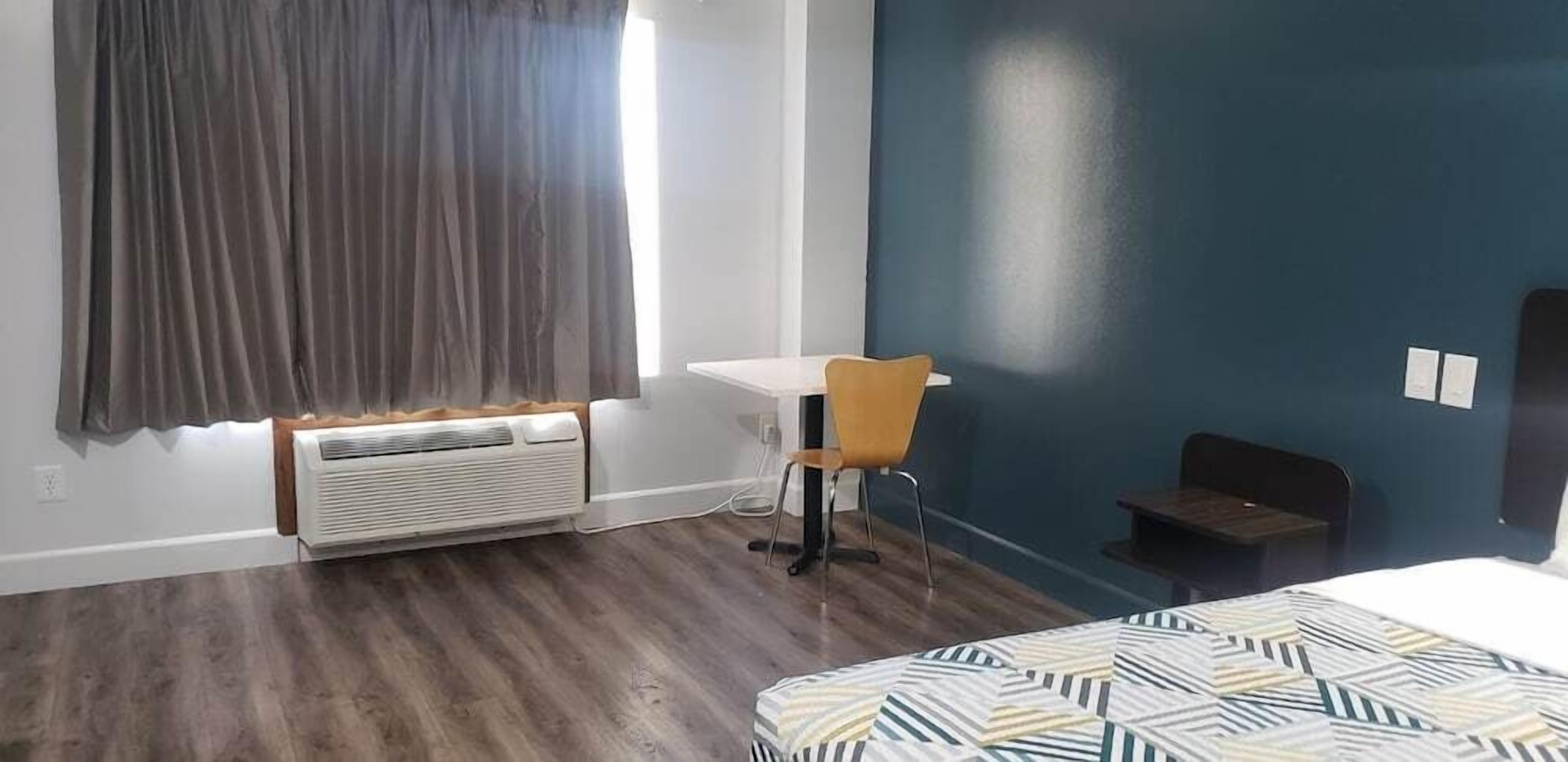 A room with a bed, a desk, a chair, and a heater.