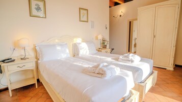 Habitación de hotel con dos camas, una mesita de noche con lámpara, un armario y un espejo.