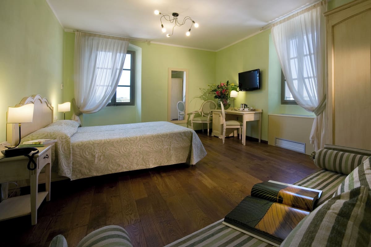 Una habitación de hotel con cama, escritorio, silla, televisor y sofá.