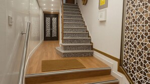 Una escalera con escalones de madera y barandillas de metal que conduce a una puerta con un panel decorativo.