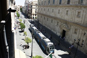 A tram moving along a street lined with historic buildings. - Catedral Boutique (Seville)