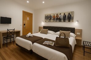 A hotel room with two beds, a desk, and a television. - Catedral Boutique (Seville)