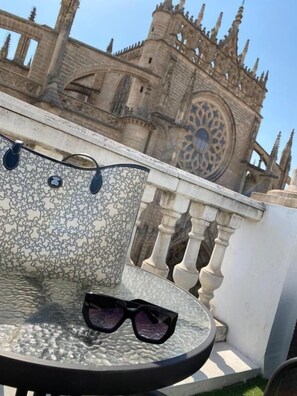 A round table with a patterned tablecloth and a pair of sunglasses on it, set against a backdrop of a historic building with intricate architecture.