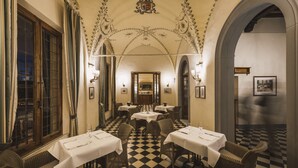 Un comedor con piso de cuadros, mesas cubiertas con manteles blancos y sillas de mimbre.