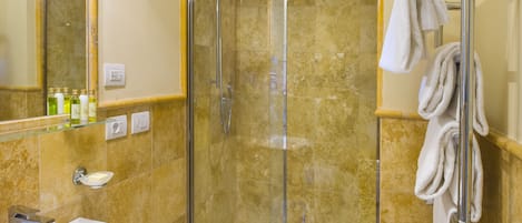 A bathroom with a glass-enclosed shower, a sink, and a towel rack with towels.
