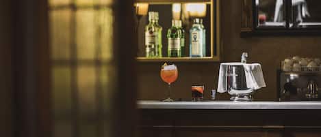 A bar area with a counter, bottles, and glasses.