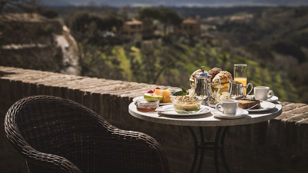 Una mesa con alimentos para el desayuno y una silla de mimbre, con vistas a un paisaje pintoresco.