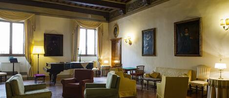 A spacious living room with a grand piano, comfortable seating, and elegant wall decorations.