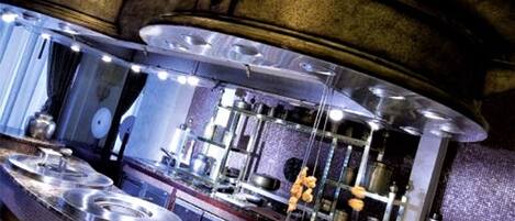 A kitchen with a large fish sculpture, stainless steel appliances, and copper pots.