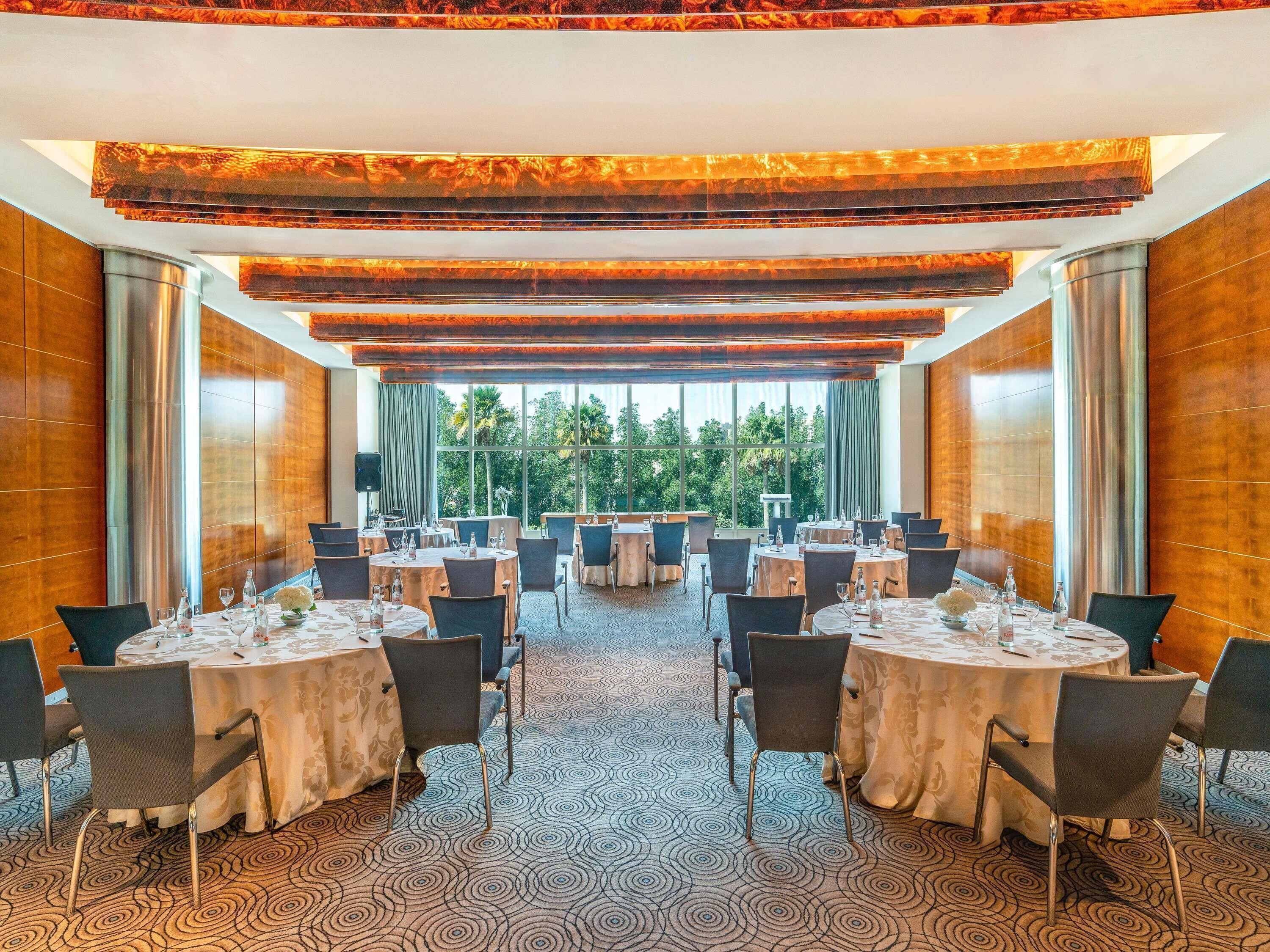 A conference room with round tables, chairs, and a patterned carpet.