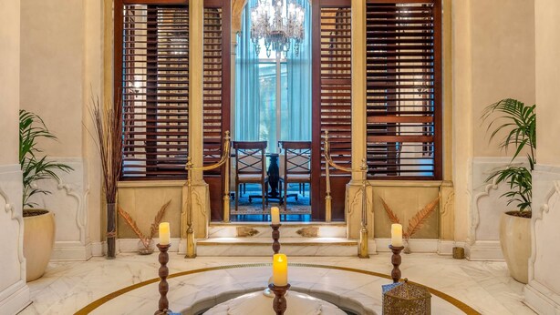 Un salón imponente con un ventanal central arqueado, candelabros y suelo de mármol.