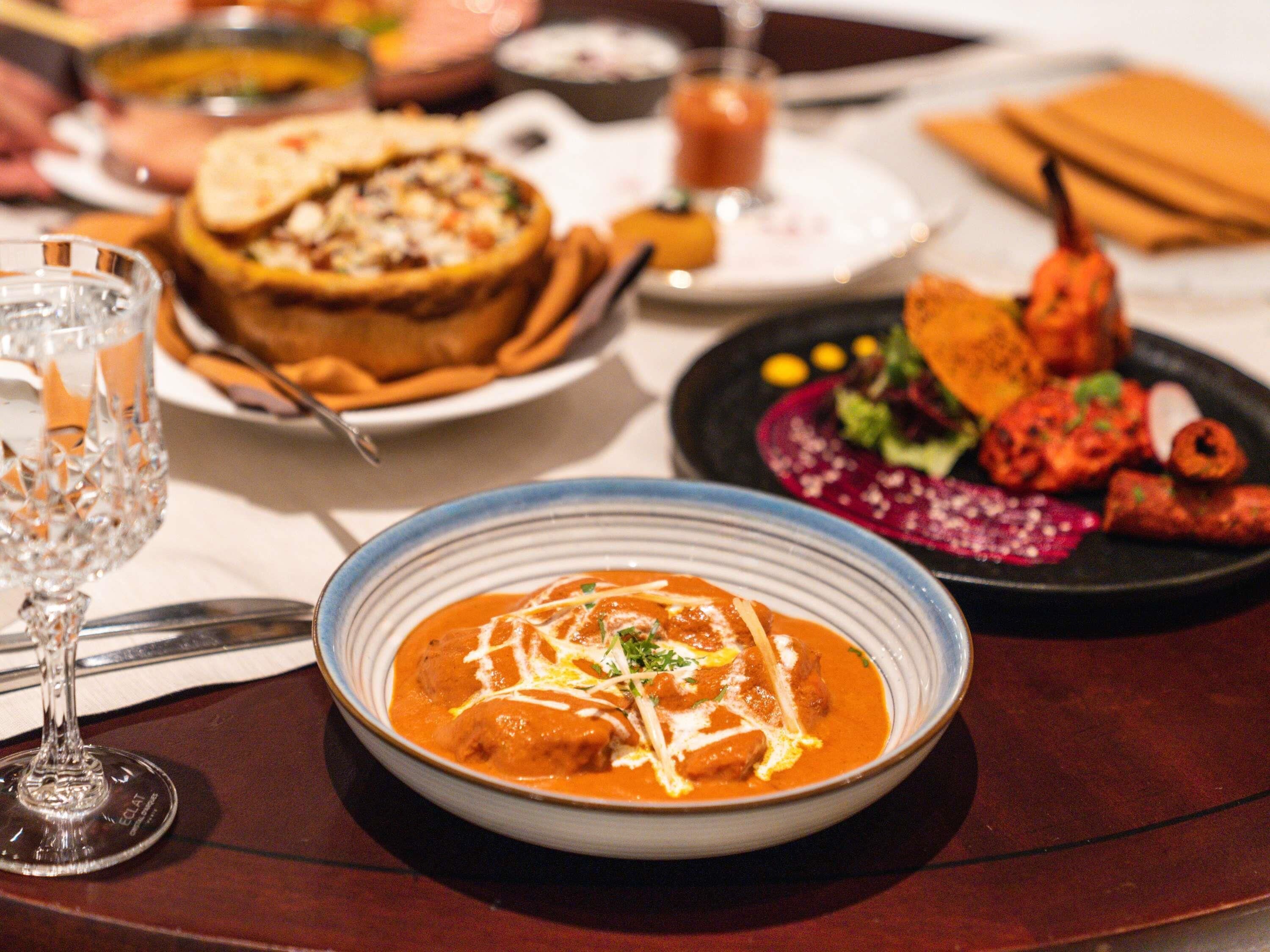 A dining table with various dishes, including a bowl of curry, bread, and a plate of vegetables.