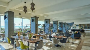 Un espacio interior amplio con una gran mesa y sillas, vista al mar y decoración moderna.