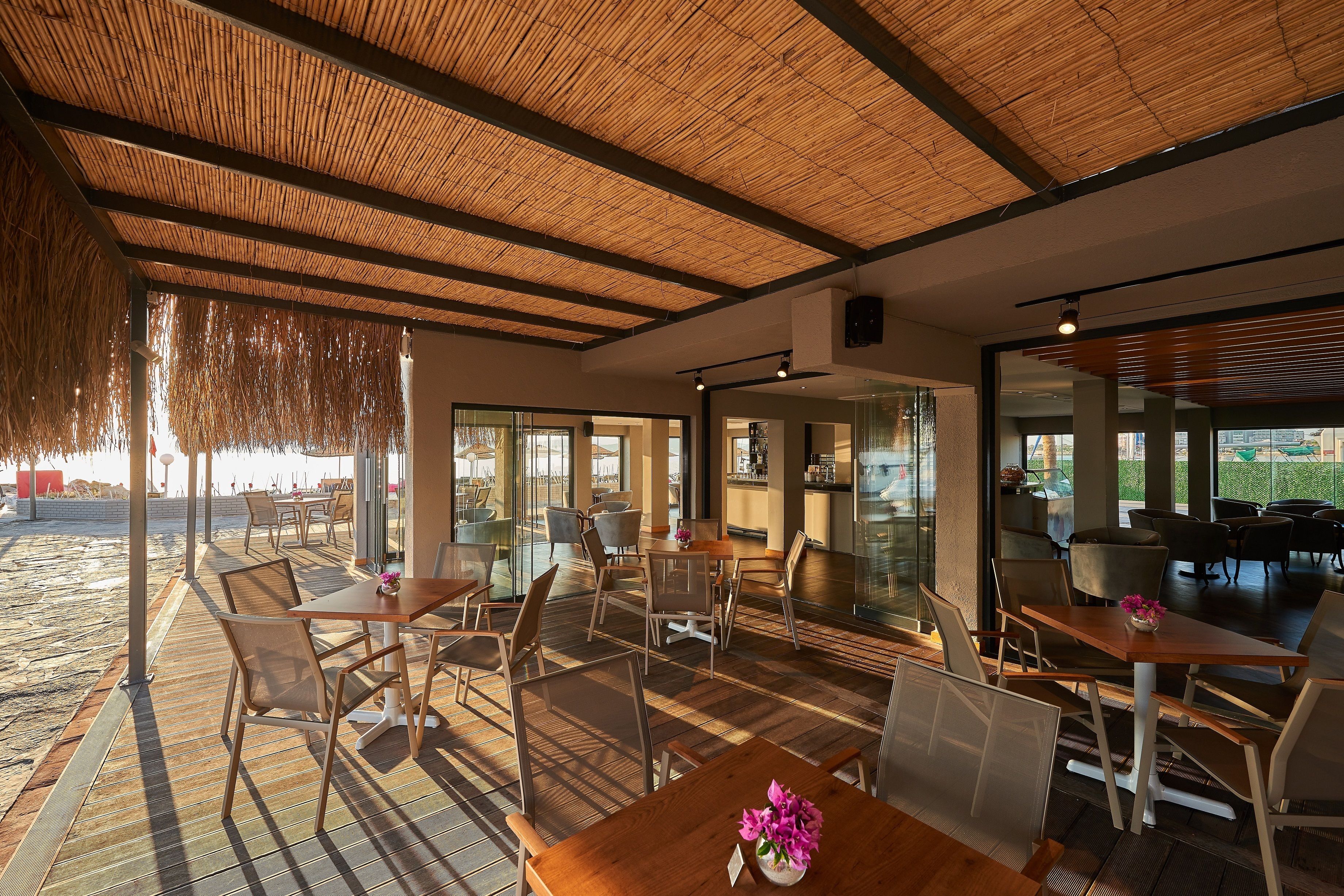A spacious indoor area with wooden flooring, tables, and chairs arranged for dining or socializing.