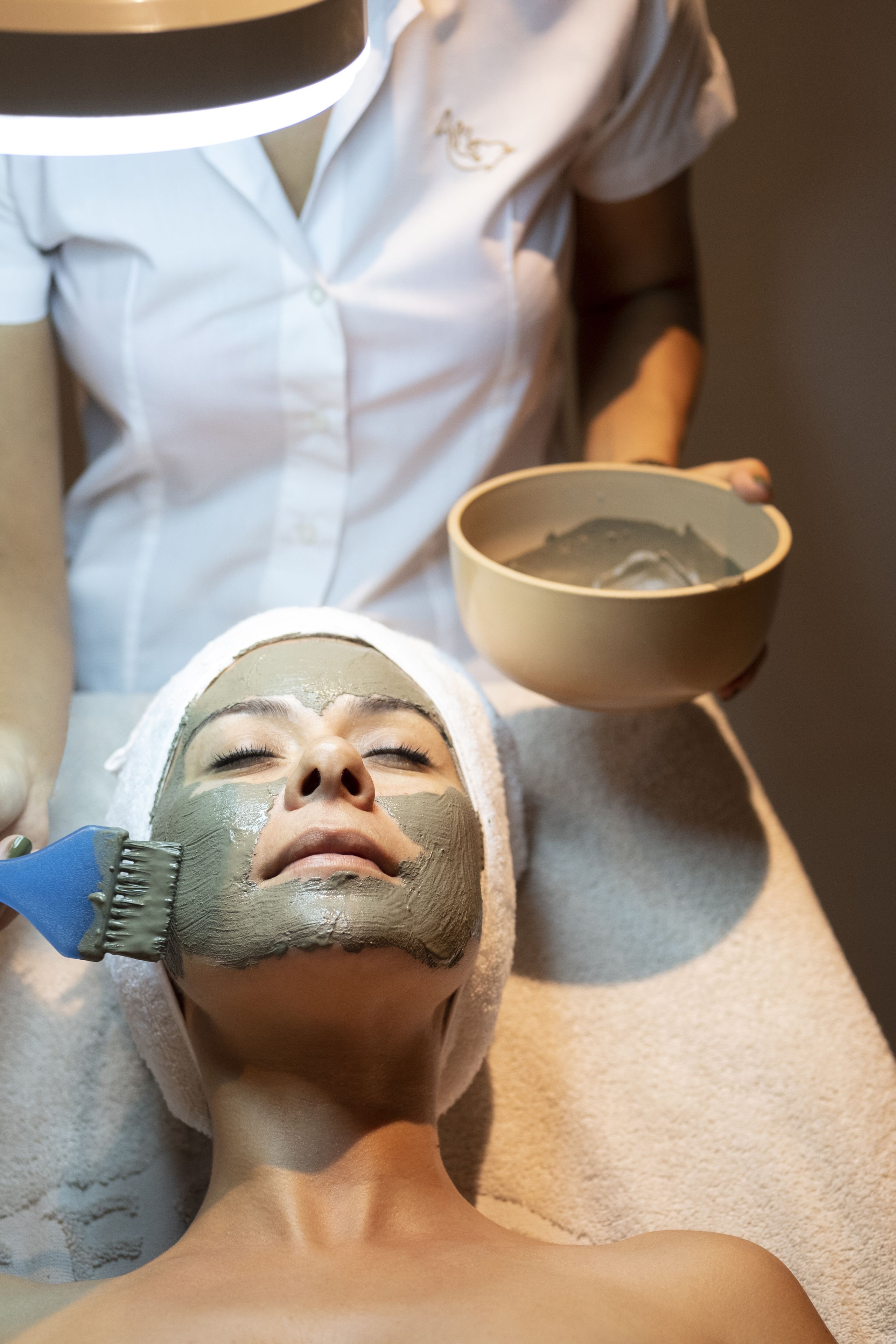 A person receiving a facial treatment with a mask applied to their face.