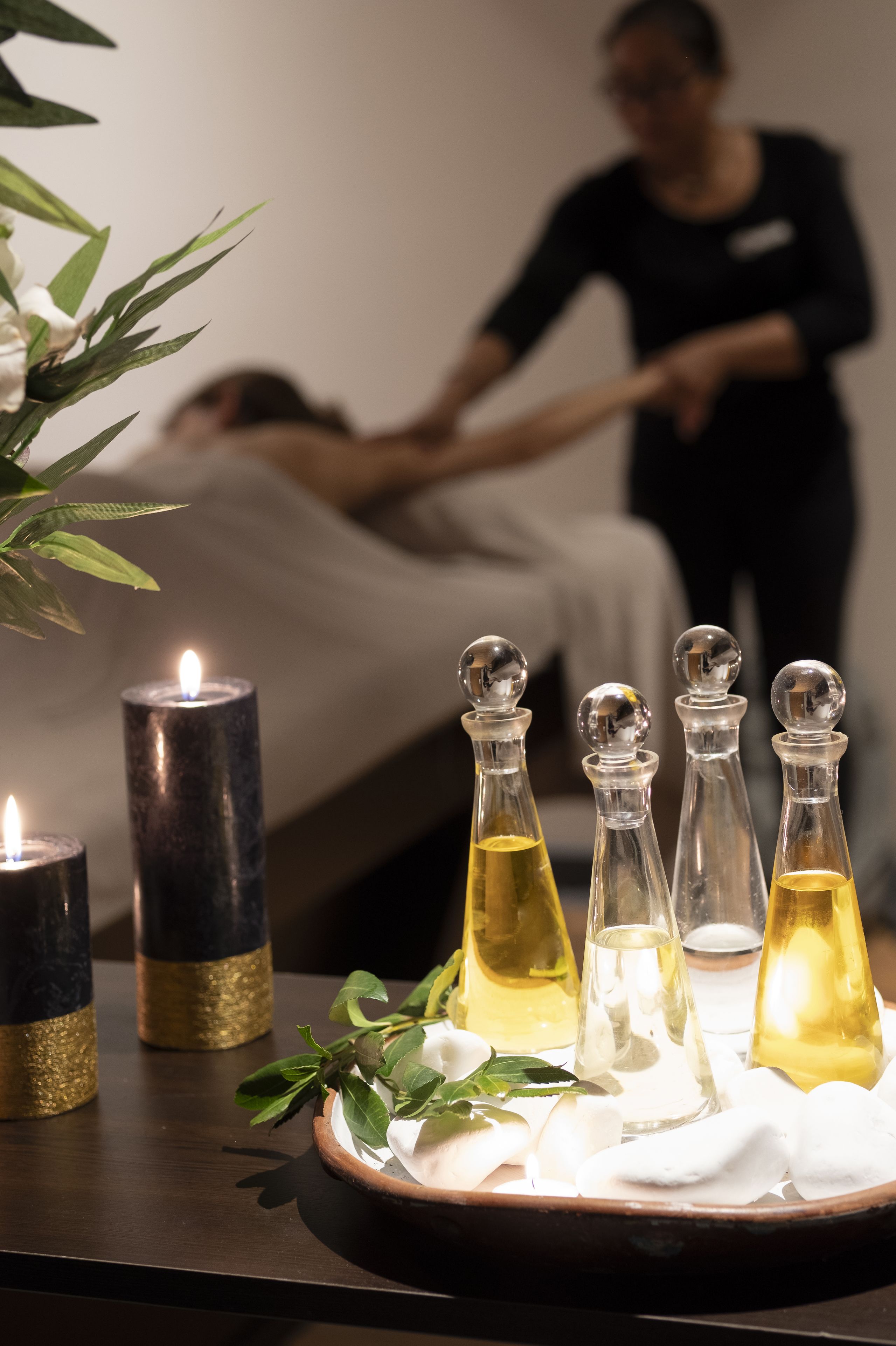 A spa setting with candles, essential oils, and a massage table.