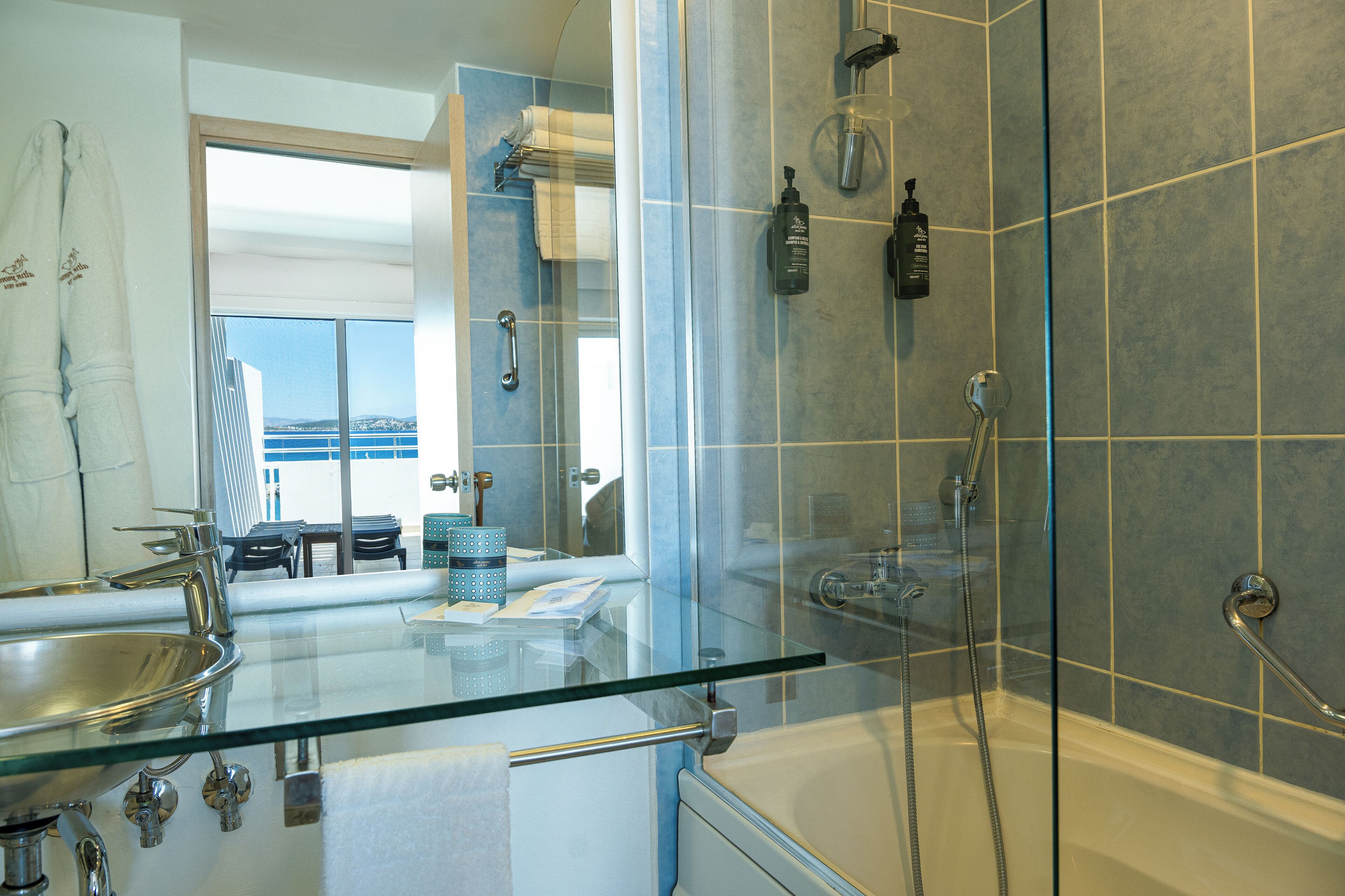 Un baño moderno con ducha envuelta en vidrio, una bañera y un lavabo de vidrio.