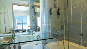 Un baño moderno con ducha envuelta en vidrio, una bañera y un lavabo de vidrio.