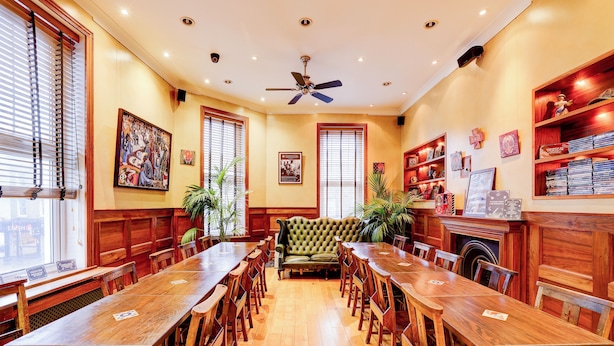 A spacious dining area with a long wooden table and chairs, a tufted sofa, and wooden shelves with books and decorative items. - Church Street Hotel by Belvilla near Kings College Hospital (London)