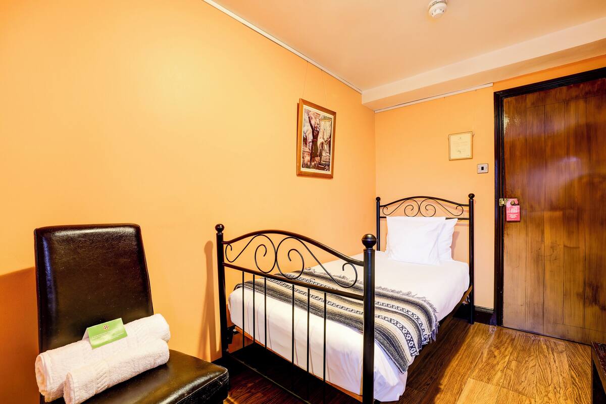 A room with a bed, a chair, and a wooden door.