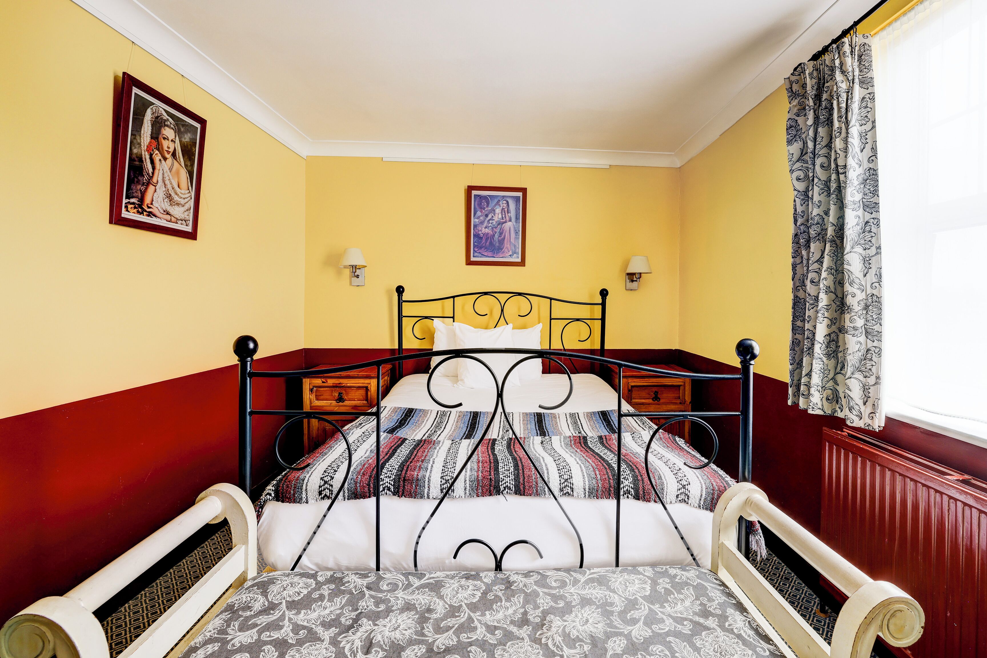Ein Zimmer mit einem Bett, zwei Wandlampen und einem fensterbelagten Fenster.