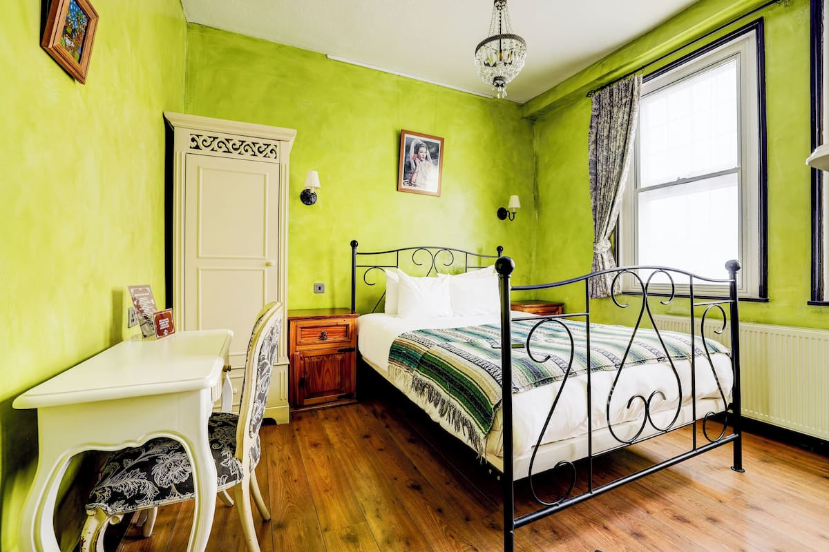 A room with a bed, a desk, a chair, and a window with curtains.