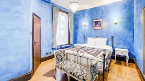 A bedroom with a bed, a chair, a nightstand, and a chandelier. - Church Street Hotel by Belvilla near Kings College Hospital (London)