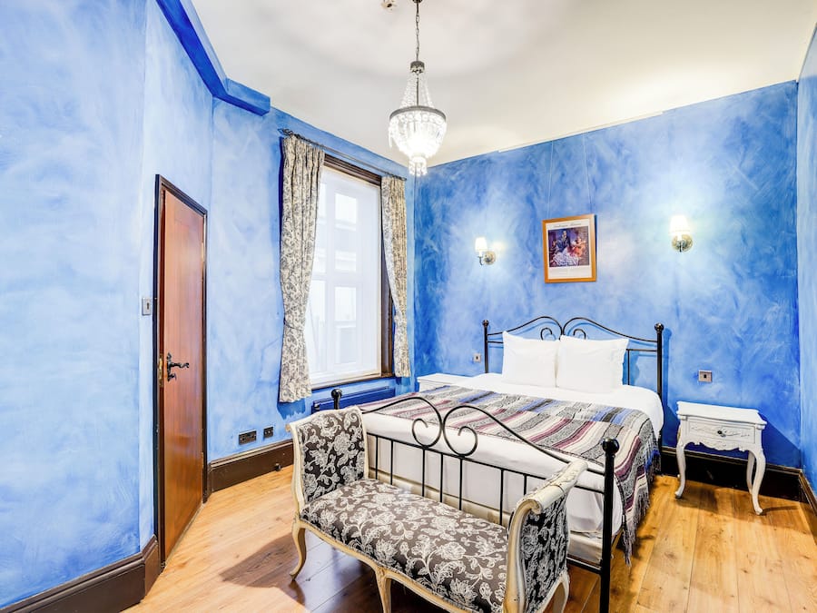 Ein Schlafzimmer mit einem Bett, einem Sessel, einem Nachttisch und einer Kronleuchter.